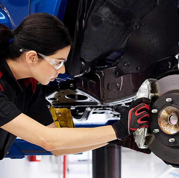 Automotive technician inspecting a vehicle brake assembly during service.