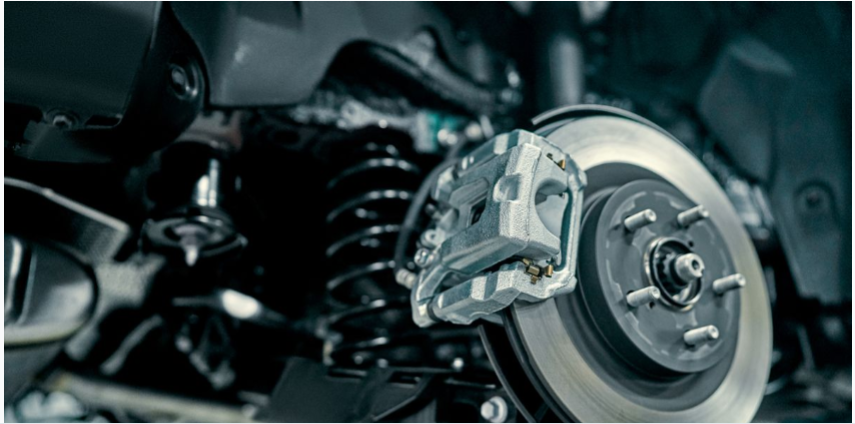 Close-up view of vehicle brake system showing brake rotor, caliper, and suspension components.